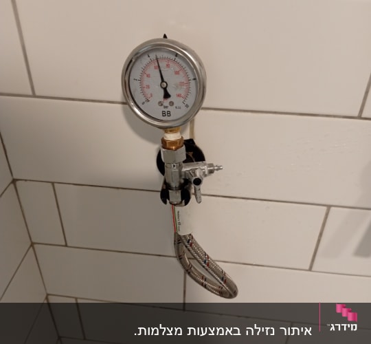 מד לחץ מחובר לצינור גמיש על קיר אריחים